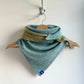 Woven scarf with a pattern on a wooden hanger against a white background