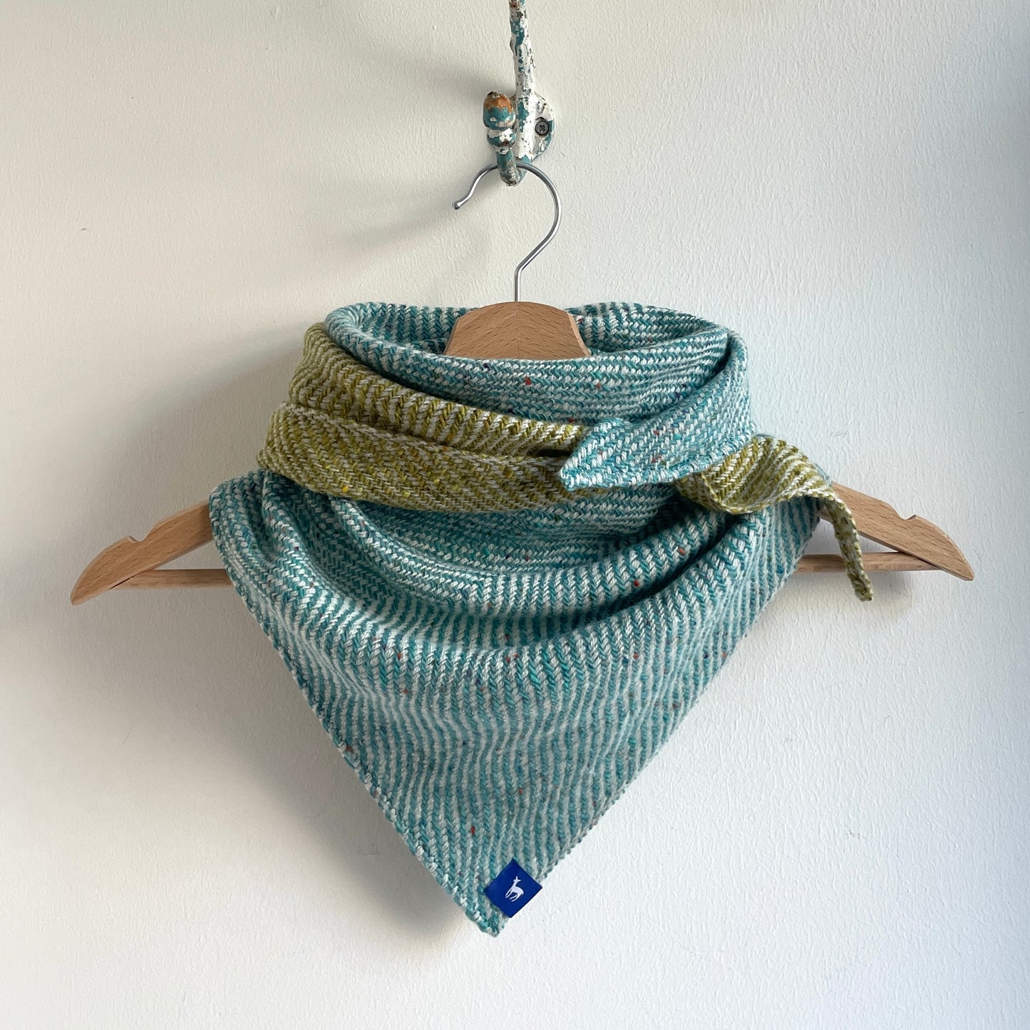 Woven scarf with a pattern on a wooden hanger against a white background