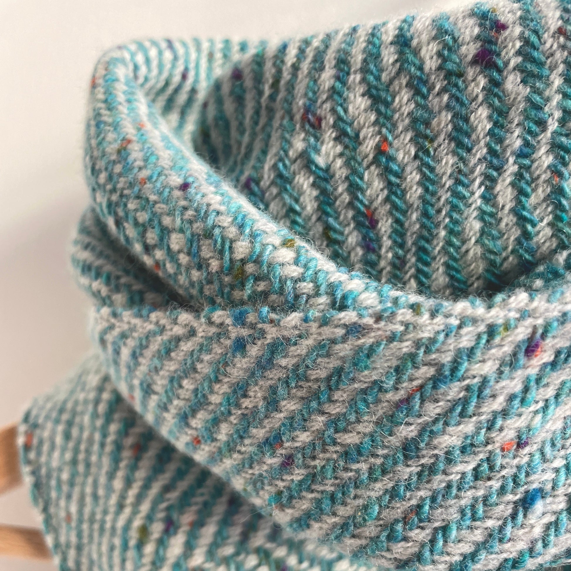 Close-up of a textured light aqua blue and gray woven fabric on a white background